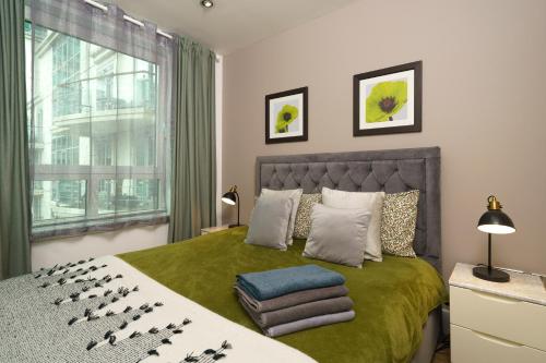 a bedroom with a bed with a green blanket at St George Wharf in London