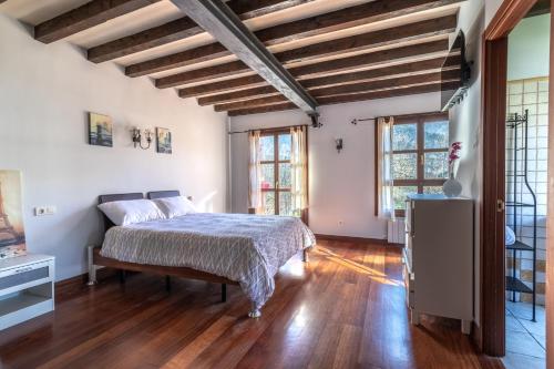 a bedroom with a bed and wooden floors and windows at Caserío Zubieta in Orózqueta