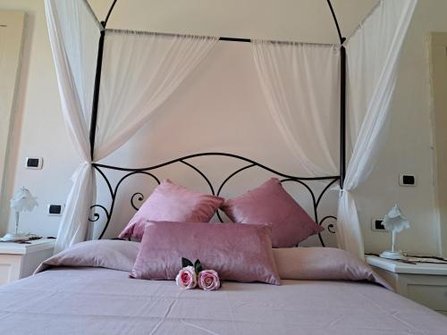 een bed met roze kussens en roze bloemen erop bij Il Castello degli ulivi in Roccella Ionica