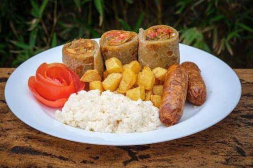 a plate of food with sausages tomatoes and rice at Galaxy Executive INN,Bar & Restaurant Wakiso in Wakiso