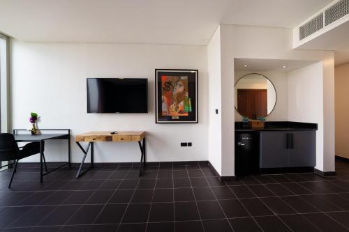 a room with a table and a tv on a wall at Emirates Sports Hotel, Dubai Sports City in Dubai