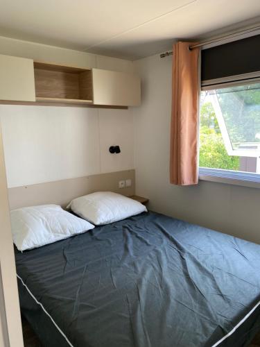 een bed in een kleine kamer met een raam bij Mobil home 8 personnes in Lattes