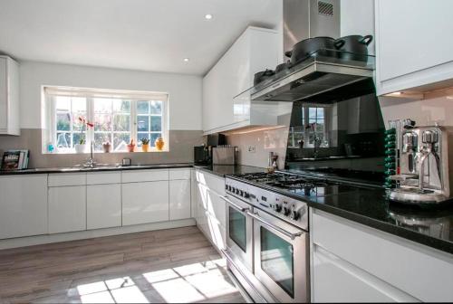 a kitchen with white cabinets and a stove top oven at BOURNECOAST: *HOT TUB*BBQ HUT*GYM*GARDEN* HB6340 in Bournemouth