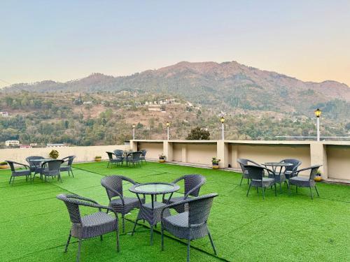 a group of tables and chairs on a patio with a mountain at Wanna Stay Bhimtal in Bhīm Tāl
