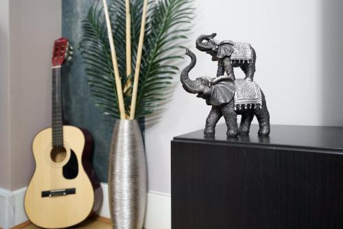 two statues of elephants on a shelf next to a guitar at St George Wharf in London
