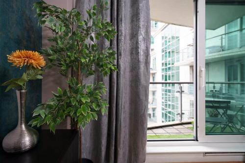 a vase with a plant on a table next to a window at St George Wharf in London