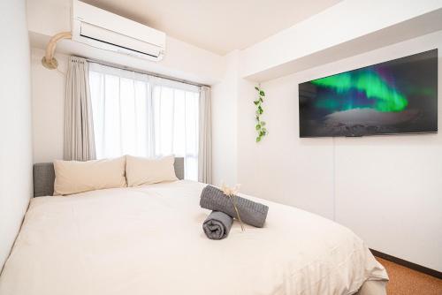a bedroom with a white bed with a tv on the wall at 新宿歌舞伎町東新宿站3分钟，徒步伊势丹4分钟免费Wi-Fi！ in Tokyo