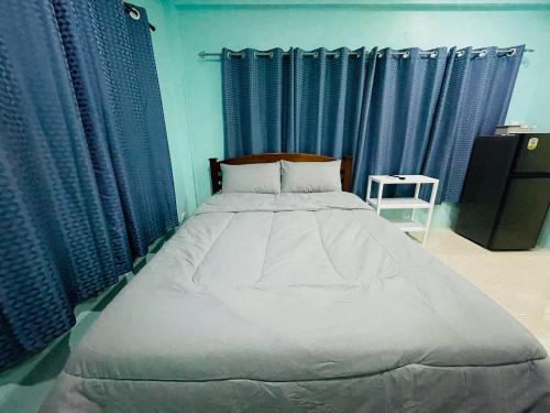 1 dormitorio con 1 cama grande y cortinas azules en NUN GUEST HOUSE, en Ban Bo Han