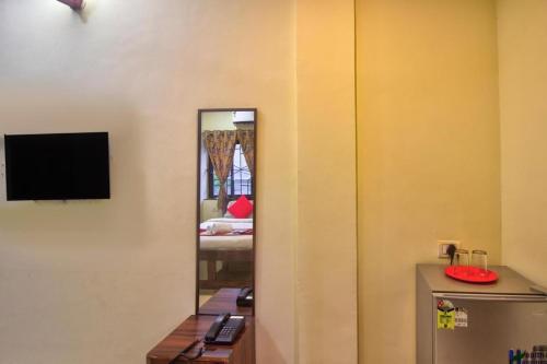 Zimmer mit einem Spiegel und einem TV an der Wand in der Unterkunft The Baga beach 24in in Calangute