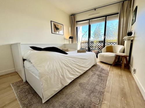 une chambre avec un grand lit blanc et un salon dans l'établissement Parisian flat Eiffel tower view, à Paris