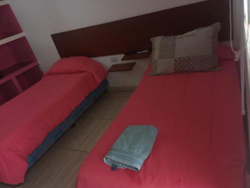 a bedroom with two beds with red sheets and a pillow at hotel el retorno in Catriel
