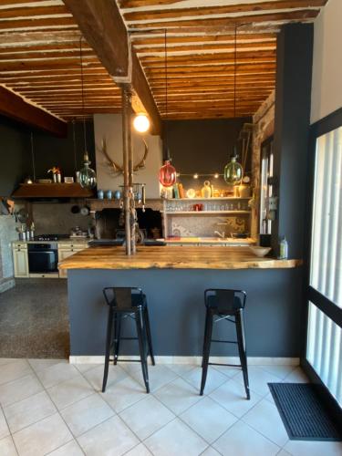 une cuisine avec deux tabourets de bar à un comptoir dans l'établissement Maison spacieuse & chaleureuse au cœur du village, à Cases-de-Pène