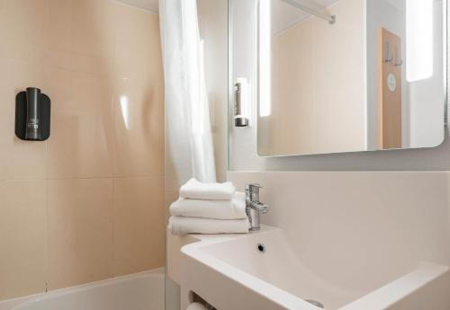 een witte badkamer met een wastafel en een spiegel bij B&B HOTEL CALAIS Coquelles Tunnel sous La Manche in Coquelles