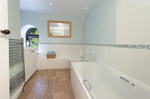 Baño blanco con bañera y espejo en Barn Owl Cottage Wheddon Cross, en Wheddon Cross