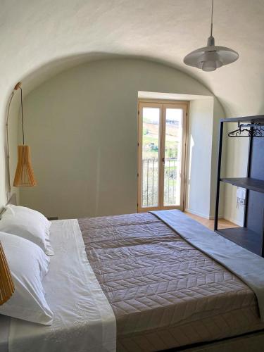 1 dormitorio con 1 cama blanca grande y ventana en B&B San Nicola, en Porchia
