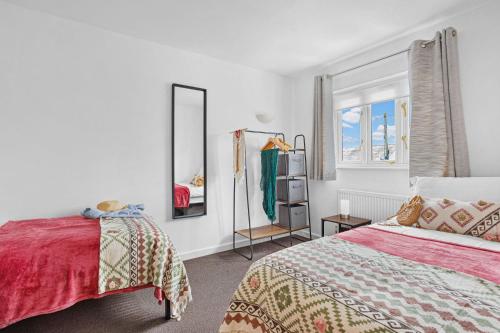 a white bedroom with a bed and a mirror at Vickery's Cottage in Woodbury