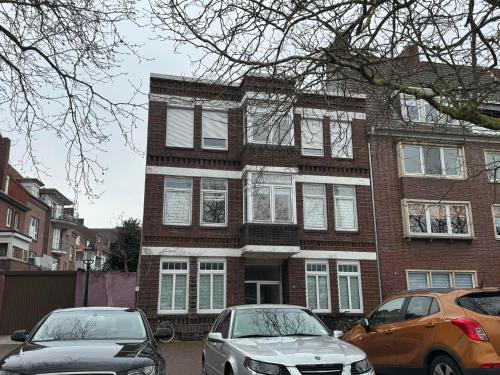 due auto parcheggiate di fronte a un edificio di mattoni di Duc Anh Ferienwohnung a Emden