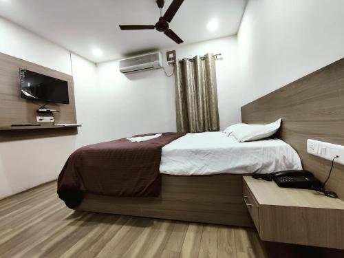 a bedroom with a large bed and a television at HOTEL NEW RATNAKAR in Daman