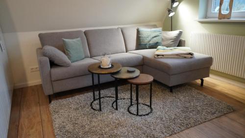 un soggiorno con divano e 2 tavoli di Haus Kiehlwasser Whg 03 OG a Boldixum