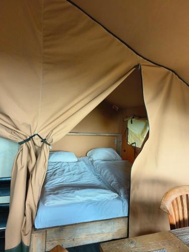 a bed in a tent in a room at Luxe safaritent in Ballum