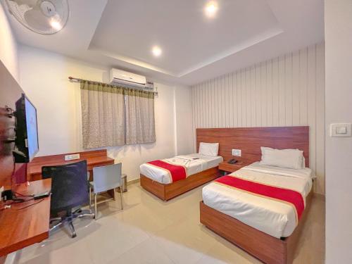 a bedroom with two beds and a desk and a computer at Aero Hotel in Yelahanka