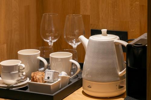 - Hervidor de té y tazas en una bandeja con copas de vino en Hotel Boutique La Pau, en Barcelona