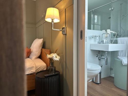 a bathroom with a sink and a toilet and a lamp at Peterhof Sarnen in Sarnen