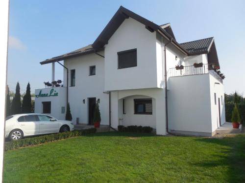 uma casa branca com um carro estacionado em frente dela em Villa AnnaLia - Rooms to Rent em Bacau