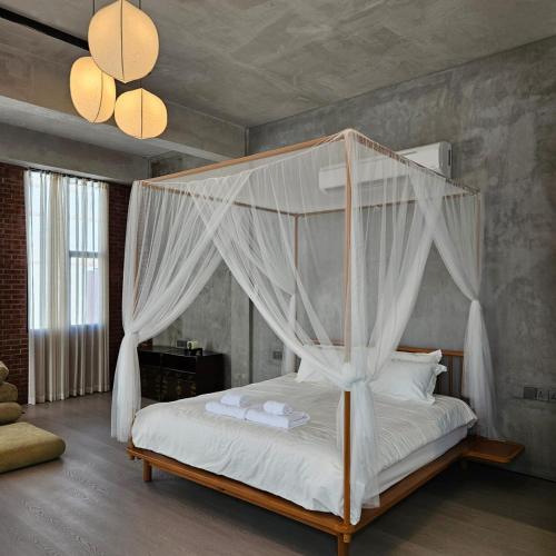 a bedroom with a canopy bed with white sheets and pillows at BASED - Mersing in Mersing