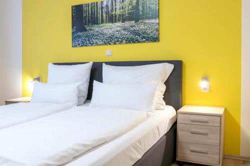 two beds in a bedroom with a yellow wall at Haus Mila in Bienenbüttel