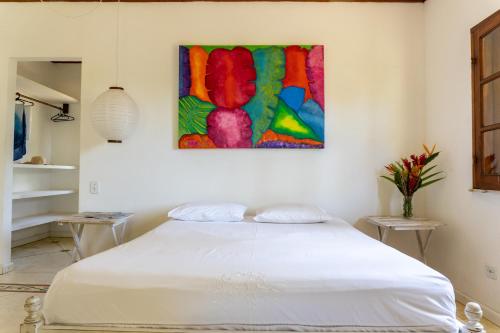 a white bed in a room with a painting on the wall at Villa Arandis in Marau