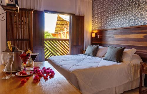 Pousada Casa do Forte في برايا دو فورتي: غرفة نوم بسرير وطاولة عليها ورد