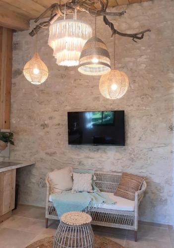 a living room with a couch and a tv and lights at Le Sens des Merveilles in Mane