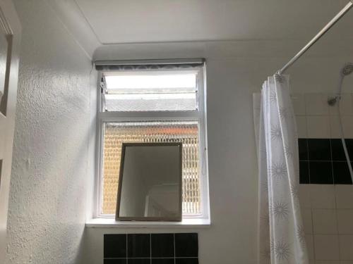 een raam in een badkamer met een spiegel en een douche bij East London 2 bedroom flat in Londen