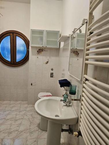 ein weißes Bad mit einem Waschbecken und einem Fenster in der Unterkunft Liberty Apartment in Mailand