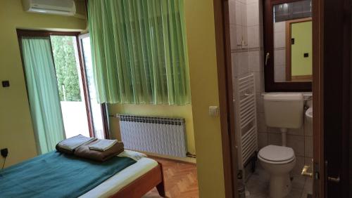 a bedroom with a bed and a toilet and a window at Mirna noć in Zagreb