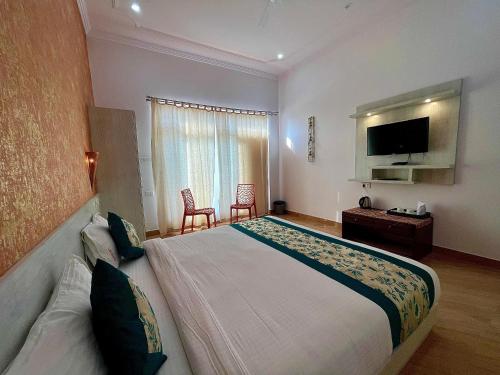 una camera con un grande letto e una TV a schermo piatto di La Curcuma Luxury Homestay a Khajurāho