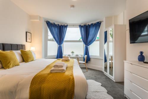 a bedroom with a large bed with blue curtains at West Street Studio Apartments in Southend in Southend-on-Sea