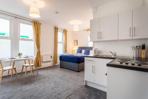 een keuken en een woonkamer met een bed en een tafel bij West Street Studio Apartments in Southend in Southend-on-Sea