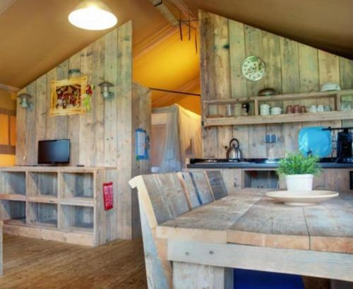 une chambre avec une table et une cuisine avec des murs en bois dans l'établissement Safaritent of Chalet, à Neede