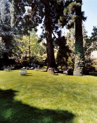 a park with chairs and trees in the grass at Parkhotel Laurin in Bolzano