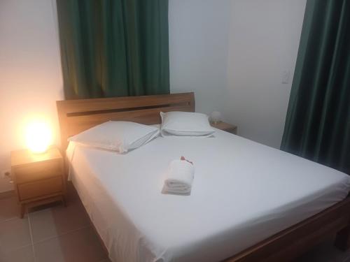 Un dormitorio con una cama blanca con una botella. en F3 Le Carbet des Anges, en Le Carbet