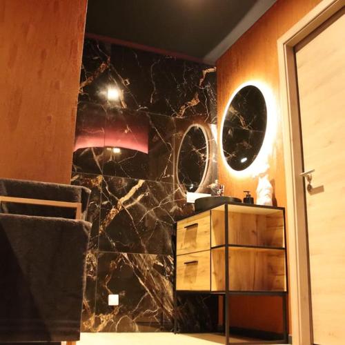 La salle de bains est pourvue d'un mur en marbre noir et d'un lavabo. dans l'établissement Les Secrets du Château - Love Room, à Lichtenberg