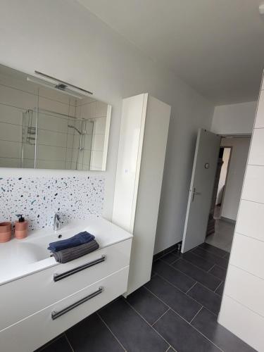 une salle de bain blanche avec un lavabo et un miroir dans l'établissement Charmante maison à Stotzheim, 1 à 6 personnes, à Stotzheim