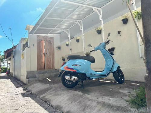 a blue scooter parked in front of a building at Y&J in Seminyak