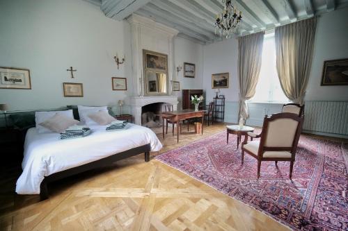 een slaapkamer met een bed en een tafel en stoelen bij Le Petit Serrant - maison d'hôtes d'exception in Bouchemaine