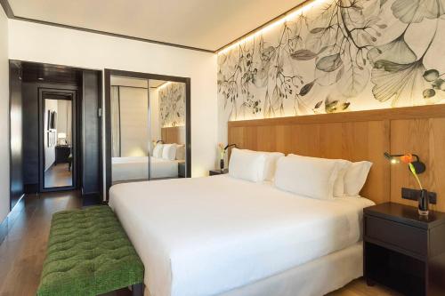 a bedroom with a large white bed with a green rug at H10 Puerta de Alcalá 4 Sup in Madrid