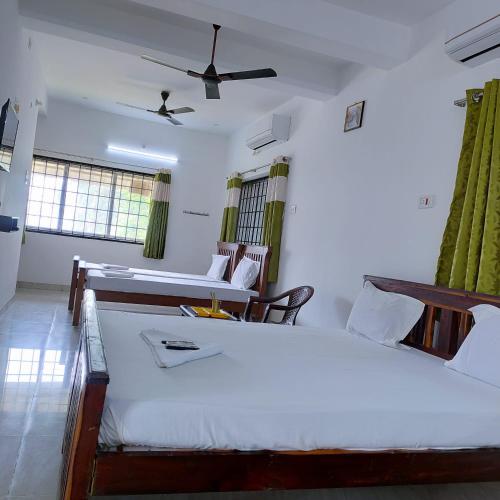 1 dormitorio con 2 camas y ventilador de techo en Ocean Sands Residency en Rāmeswaram