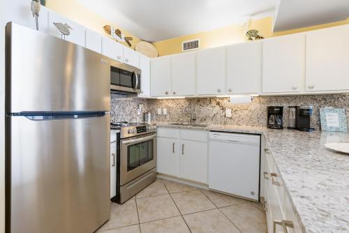 a kitchen with white cabinets and a stainless steel refrigerator at Romar Place Unit 904 in Orange Beach