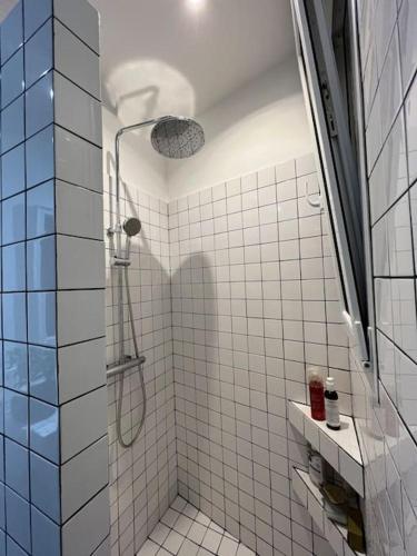 een wit betegelde badkamer met een douche. bij Charme et confort à 10 minutes du centre de Paris in Courbevoie